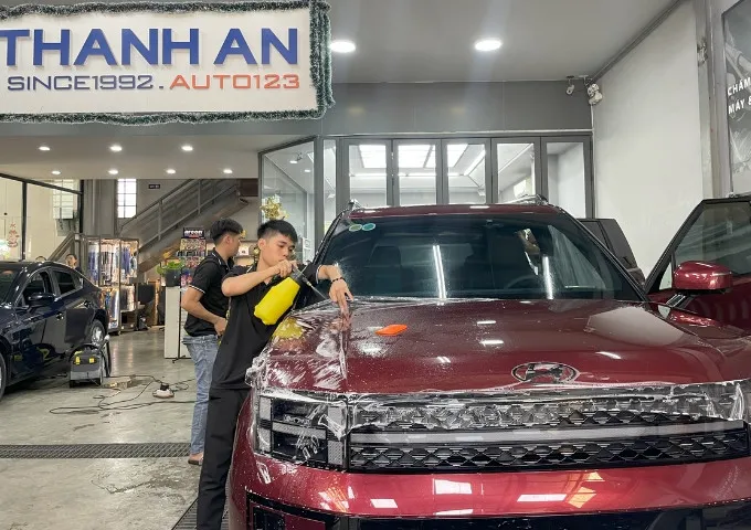Kỹ thuật viên đang dán PPF xe ô tô để bảo vệ lớp sơn zin.
