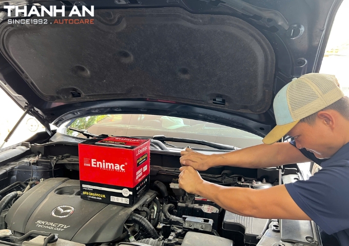 Kỹ thuật viên thay bình ắc quy Enimac cho xe ô tô Mazda tại cửa hàng tphcm