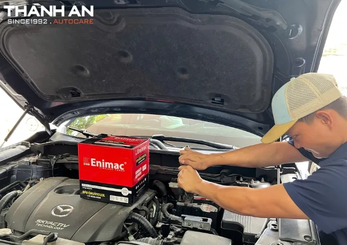 Kỹ thuật viên thay bình ắc quy Enimac cho xe ô tô Mazda tại cửa hàng tphcm
