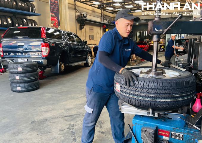 Kỹ thuật viên đang thay lốp Bridgestone 265/60R18 Dueler H/T 684 Thái Lan cho xe SUV tại gara