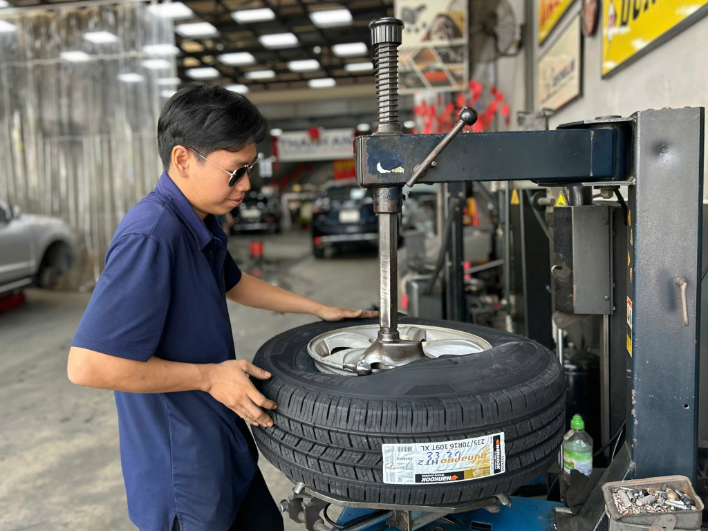 Kỹ thuật viên hỗ trợ khách hàng thay lốp Hankook 235/70r16 cho dòng xe gầm cao tại gara Thanh An AutoCare.
