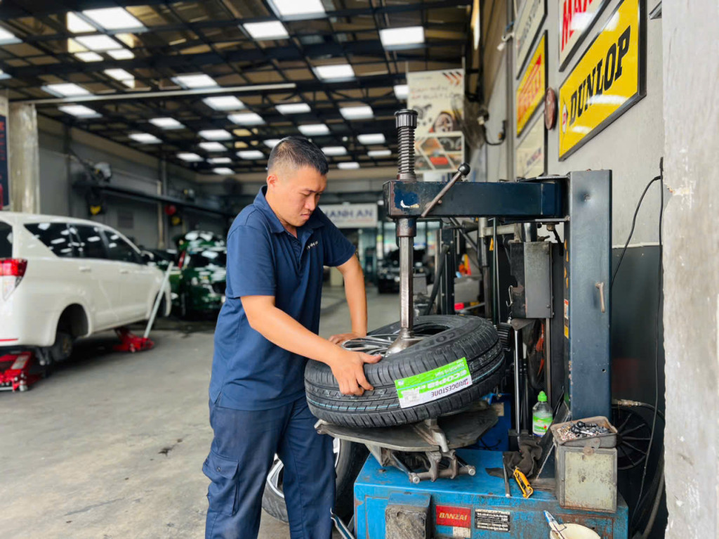 Kỹ thuật viên tại gara thay vỏ Bridgestone 205/65R16 EP150 mới cho khách chạy xe Toyota Innova